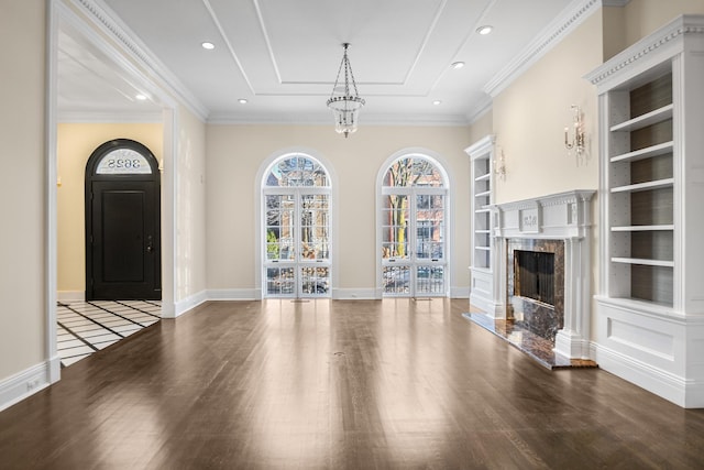 unfurnished living room featuring built in shelves, dark hardwood / wood-style floors, crown molding, and a fireplace