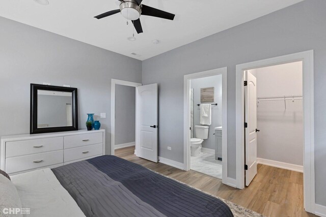 bedroom with ensuite bath, ceiling fan, a walk in closet, a closet, and light wood-type flooring