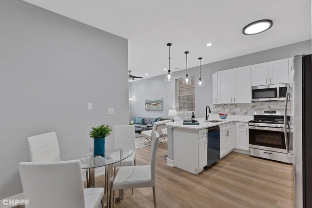 kitchen with pendant lighting, white cabinets, appliances with stainless steel finishes, tasteful backsplash, and kitchen peninsula