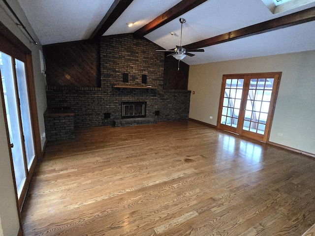 unfurnished living room featuring vaulted ceiling with beams, ceiling fan, light hardwood / wood-style flooring, and a brick fireplace