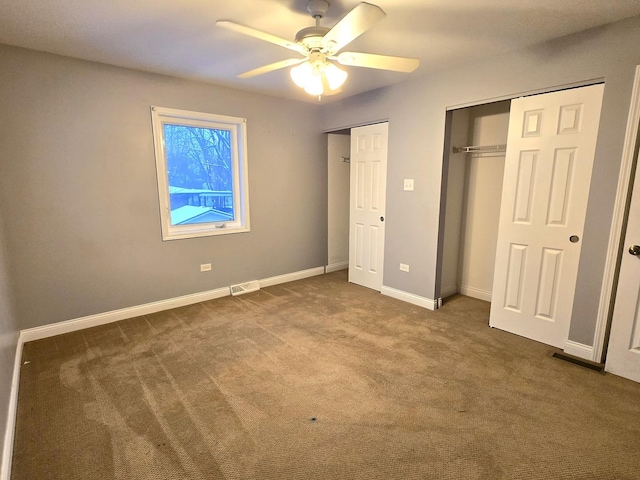 unfurnished bedroom featuring carpet floors, ceiling fan, and multiple closets