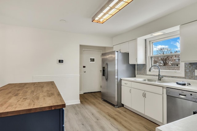 kitchen with decorative backsplash, stainless steel appliances, sink, white cabinets, and light hardwood / wood-style floors