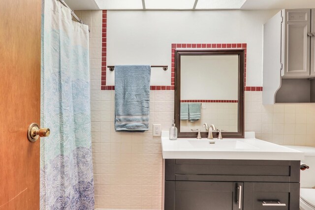 bathroom featuring tasteful backsplash, vanity, tile walls, and toilet