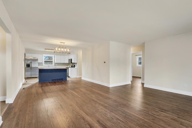 unfurnished living room with hardwood / wood-style floors and a chandelier