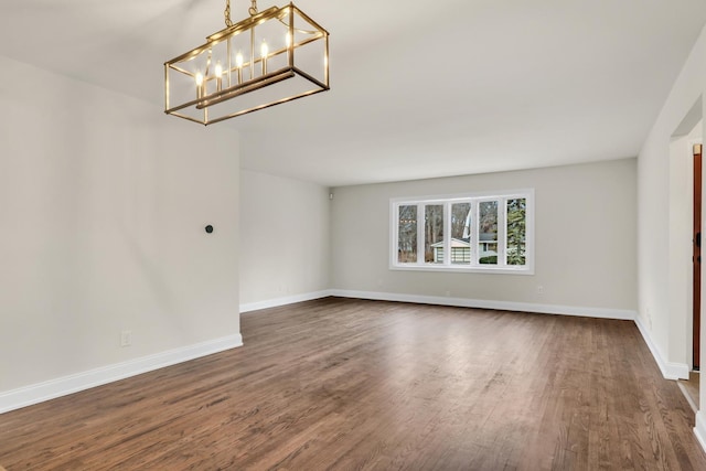 spare room featuring a notable chandelier and dark hardwood / wood-style flooring