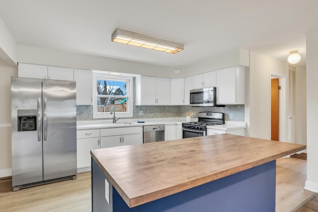 kitchen with white cabinetry, sink, tasteful backsplash, appliances with stainless steel finishes, and light wood-type flooring