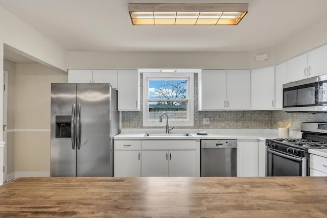 kitchen featuring backsplash, white cabinetry, sink, and appliances with stainless steel finishes