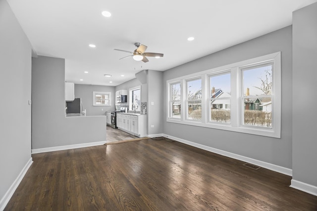 unfurnished living room with ceiling fan, dark hardwood / wood-style floors, and sink