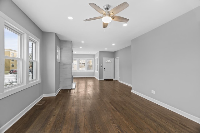 unfurnished living room with ceiling fan and dark wood-type flooring