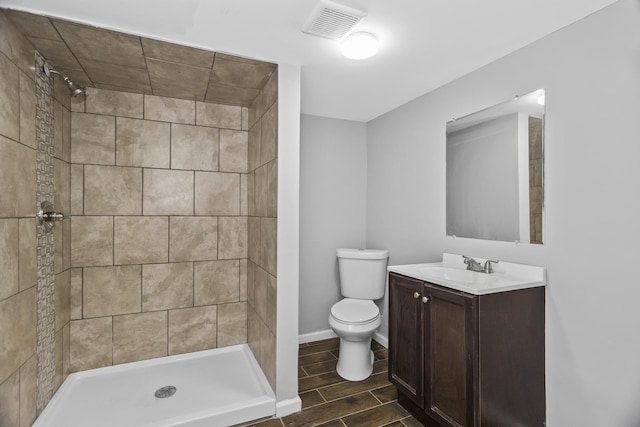 bathroom featuring tiled shower, vanity, and toilet