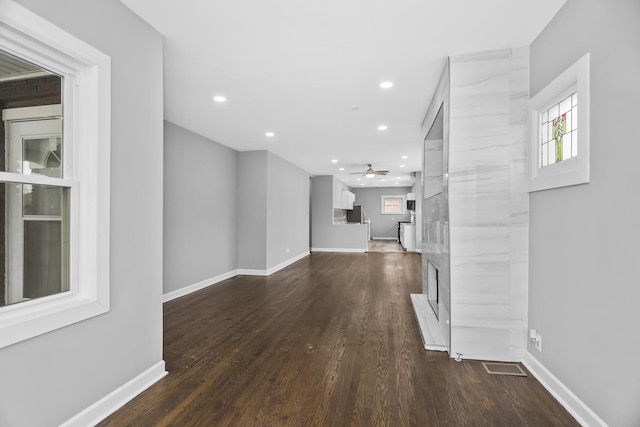 unfurnished living room featuring ceiling fan and dark hardwood / wood-style flooring