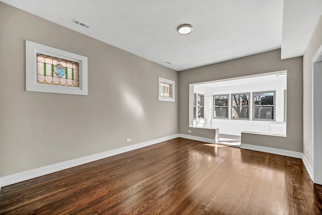 spare room featuring baseboards, visible vents, and wood finished floors