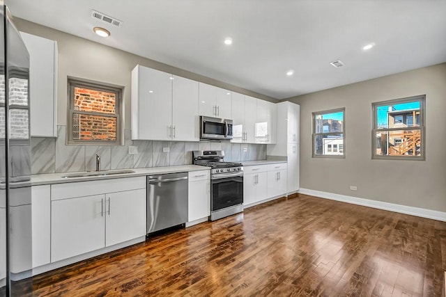 kitchen with stainless steel appliances, light countertops, visible vents, backsplash, and a sink