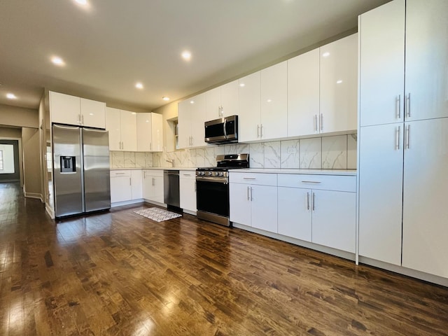 kitchen with dark wood-style floors, tasteful backsplash, light countertops, appliances with stainless steel finishes, and white cabinets