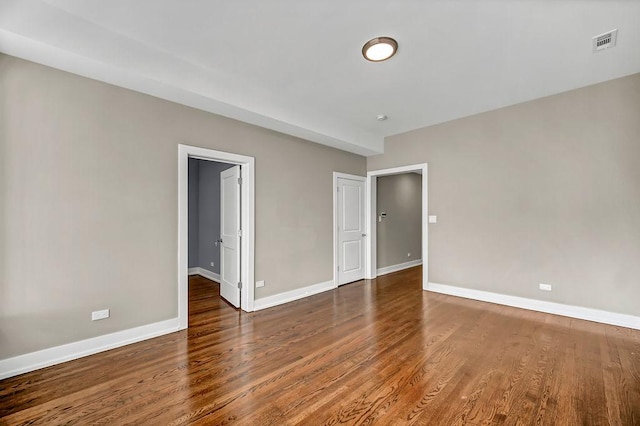 unfurnished room featuring visible vents, baseboards, and wood finished floors