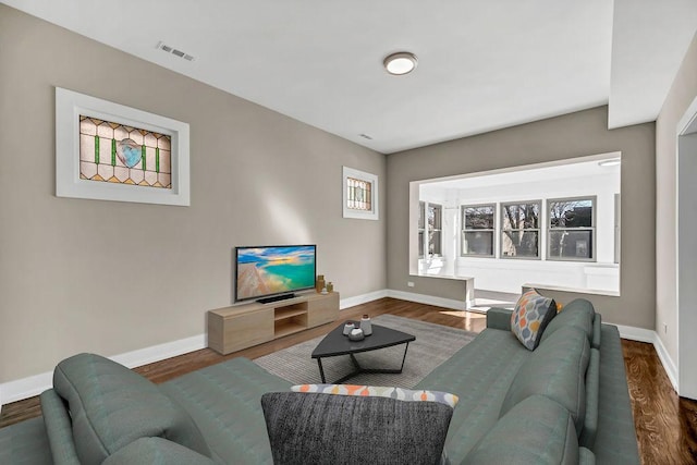 living area featuring baseboards, visible vents, and wood finished floors