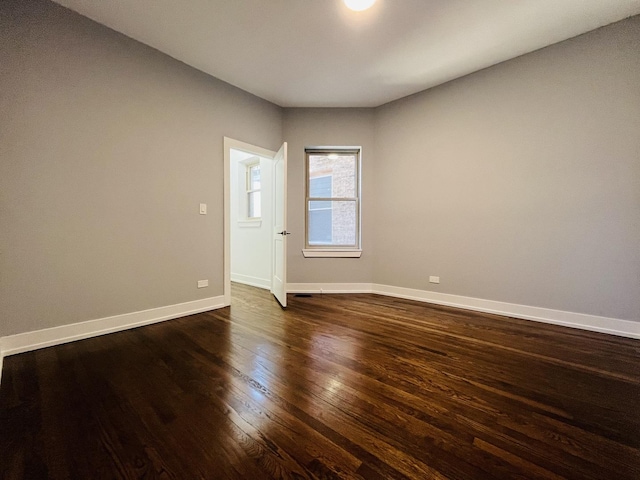 unfurnished room with dark wood-style flooring and baseboards