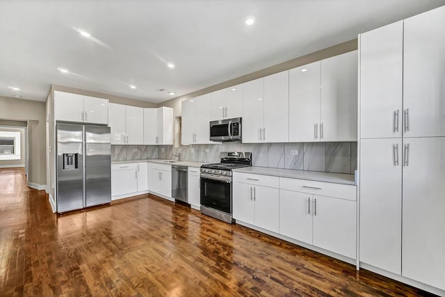 kitchen featuring tasteful backsplash, stainless steel appliances, dark wood finished floors, and light countertops