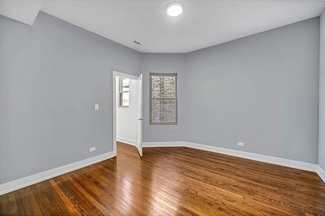 spare room with visible vents, baseboards, and dark wood-type flooring