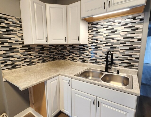 kitchen with sink, backsplash, white cabinets, and hardwood / wood-style floors