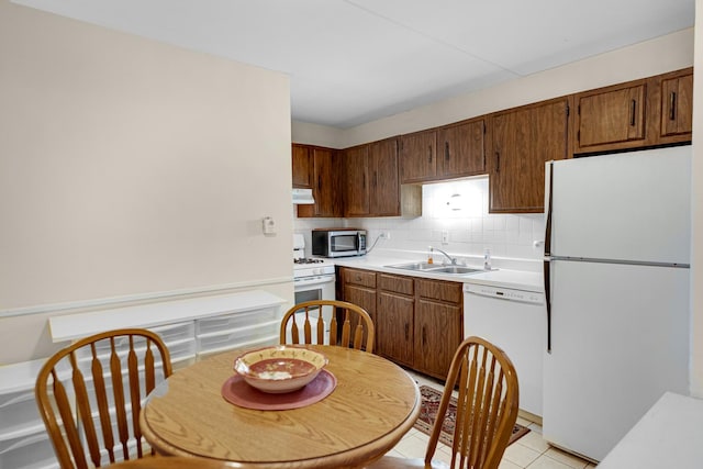 kitchen featuring sink, light tile patterned floors, backsplash, and white appliances