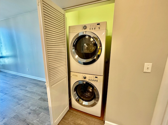 laundry room with hardwood / wood-style floors and stacked washer / drying machine