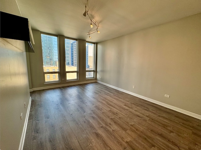 empty room featuring rail lighting and dark wood-type flooring