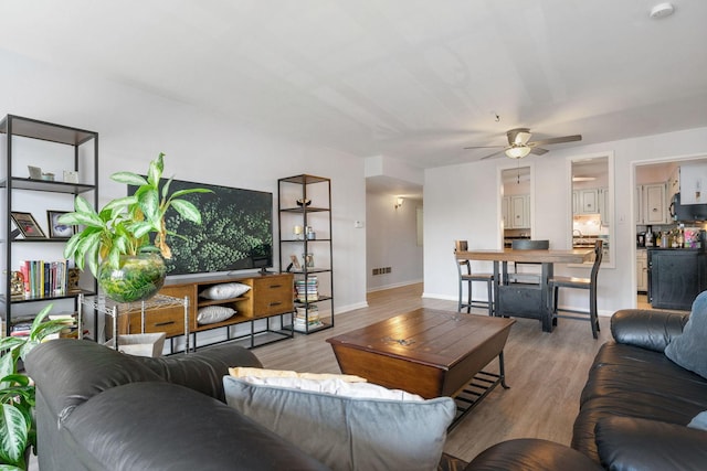 living room featuring ceiling fan and light hardwood / wood-style floors