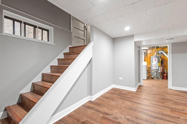 staircase featuring hardwood / wood-style floors, gas water heater, and washer / dryer