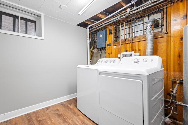 laundry room featuring wood-type flooring, electric panel, and washing machine and clothes dryer