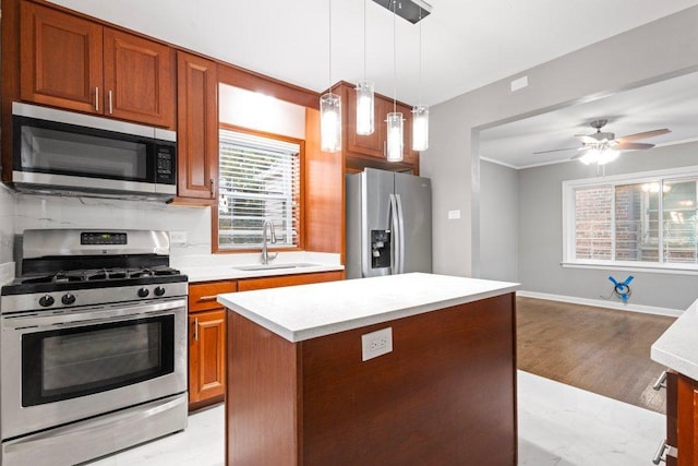 kitchen featuring a center island, hanging light fixtures, sink, ceiling fan, and appliances with stainless steel finishes