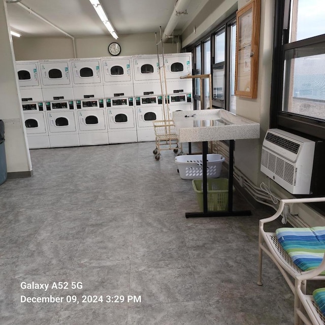 laundry room with washer and clothes dryer, stacked washer / drying machine, and an AC wall unit