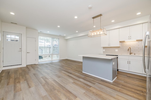 kitchen featuring white cabinetry, sink, light hardwood / wood-style flooring, decorative light fixtures, and decorative backsplash