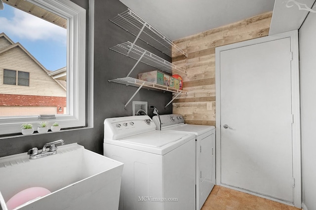 washroom featuring sink, wooden walls, and independent washer and dryer