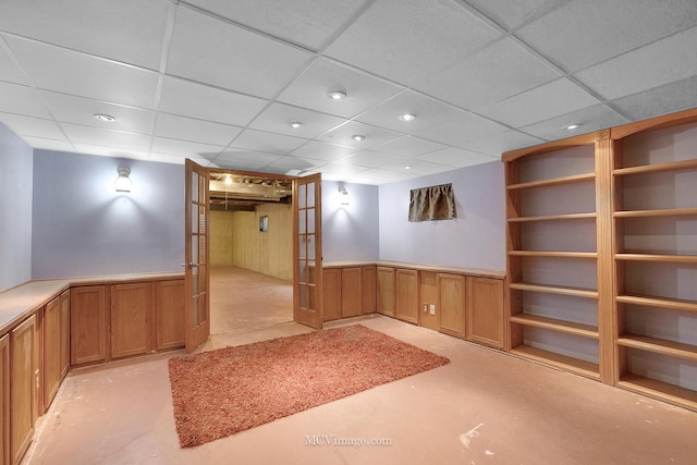 basement featuring a paneled ceiling and french doors