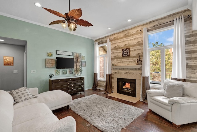 living room with dark hardwood / wood-style flooring, a wealth of natural light, ornamental molding, and a tile fireplace