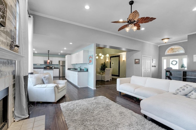 living room featuring ceiling fan, a fireplace, ornamental molding, and dark hardwood / wood-style flooring