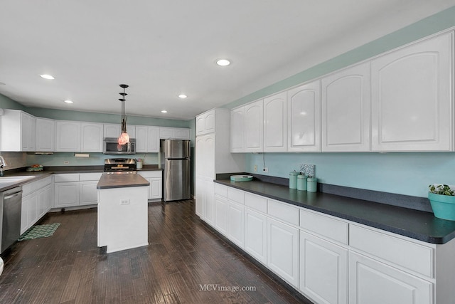 kitchen featuring white cabinetry, stainless steel appliances, a center island, dark hardwood / wood-style flooring, and decorative light fixtures