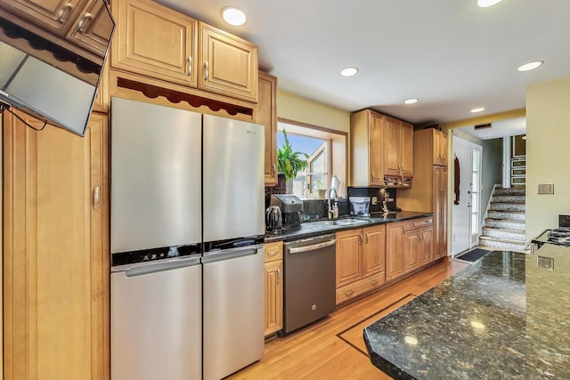 kitchen featuring light hardwood / wood-style floors, sink, appliances with stainless steel finishes, and dark stone counters