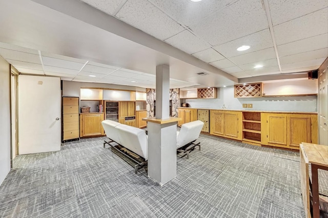 kitchen with a kitchen bar, a paneled ceiling, light carpet, and kitchen peninsula