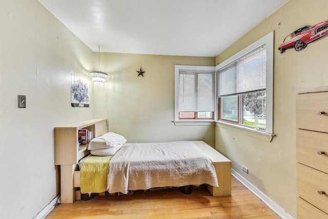 bedroom with hardwood / wood-style flooring and an inviting chandelier