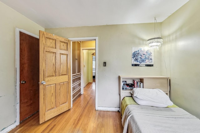 bedroom with a chandelier and light wood-type flooring