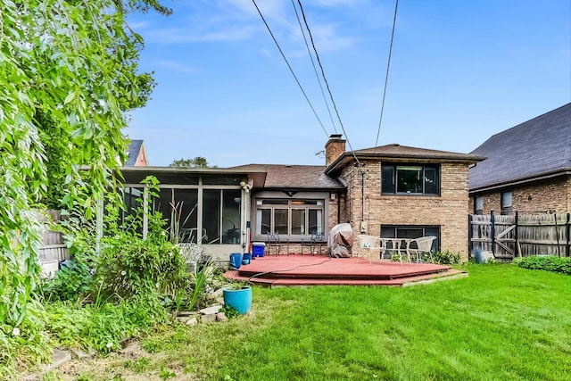 rear view of house with a sunroom, a deck, and a lawn