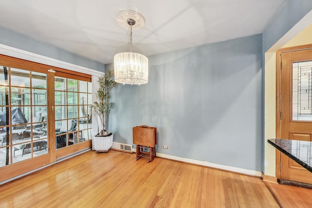 unfurnished room featuring a notable chandelier and light wood-type flooring