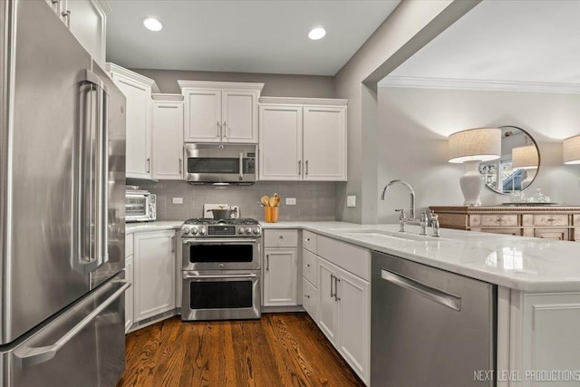 kitchen with sink, stainless steel appliances, light stone countertops, white cabinets, and kitchen peninsula