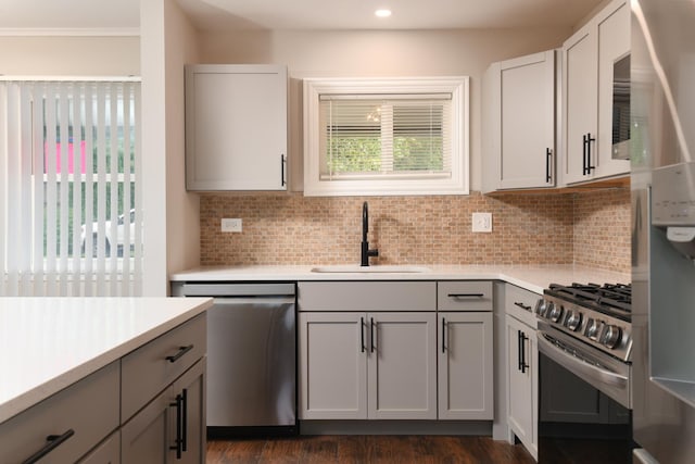 kitchen featuring gray cabinetry, sink, dark hardwood / wood-style floors, appliances with stainless steel finishes, and tasteful backsplash