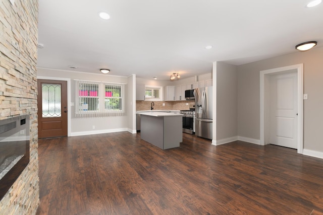 kitchen with tasteful backsplash, stainless steel appliances, a center island, dark hardwood / wood-style floors, and white cabinetry