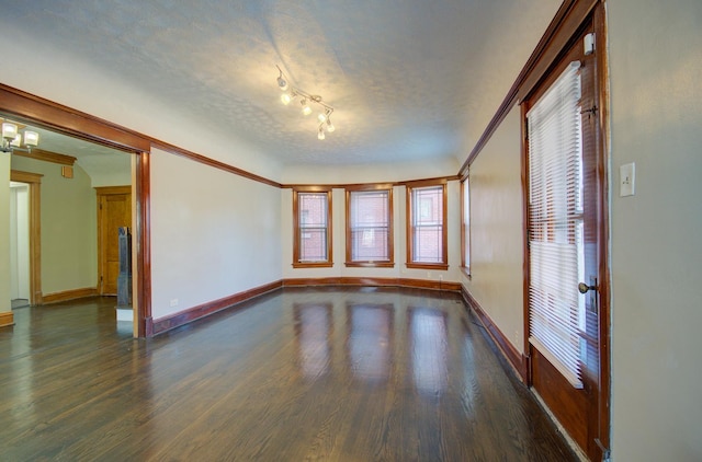 unfurnished room featuring ornamental molding, a textured ceiling, and dark wood-type flooring