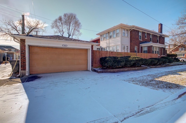 view of snow covered exterior featuring a garage and an outbuilding