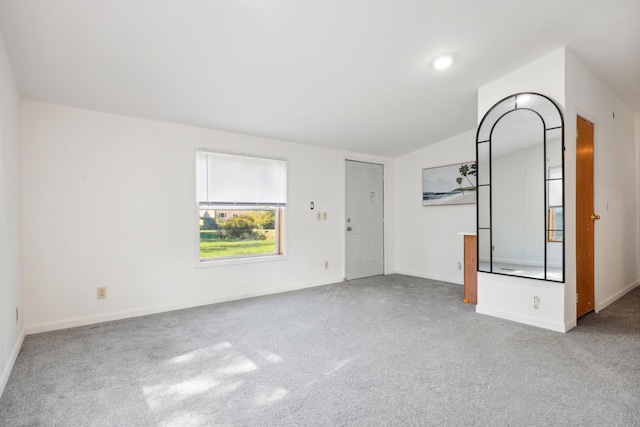 unfurnished living room featuring light carpet and vaulted ceiling